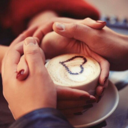 happy couple with a cup of coffee with a heart in the foam