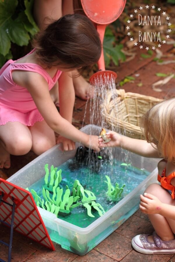 toddlers playing with a water sensory bin outdoors