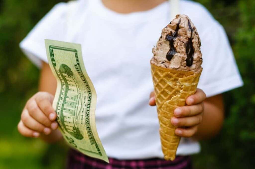 girl holding ice cream cone and money as rewards