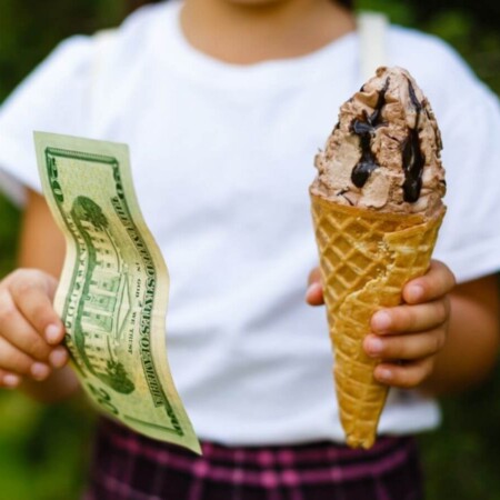 girl holding ice cream cone and money as rewards