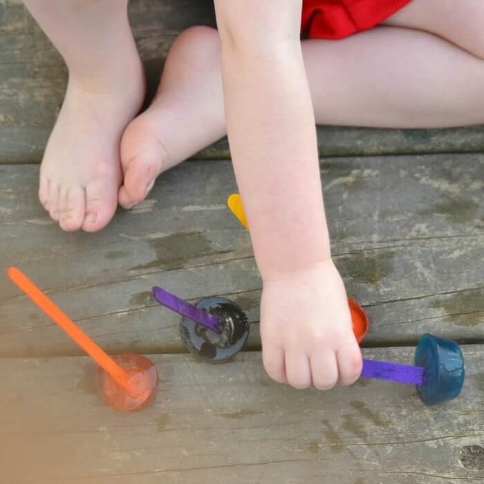 toddler painting with colored ice cubes outside