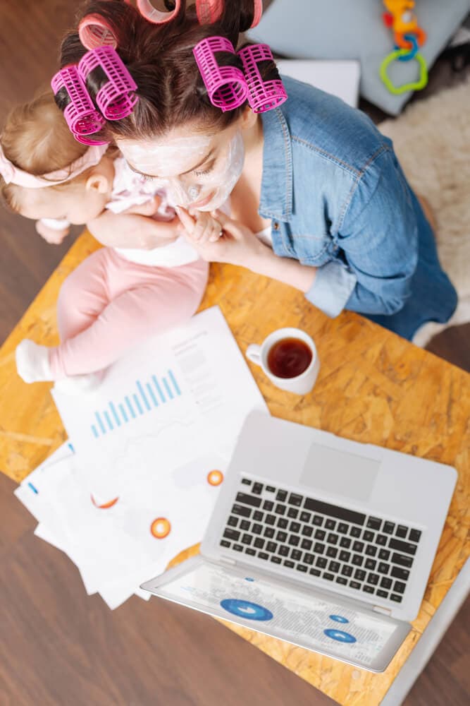 a modern homemaker holding a baby and working