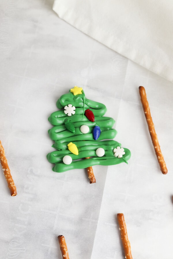 drizzled green melting chocolate on a pretzel stick to form a Christmas tree