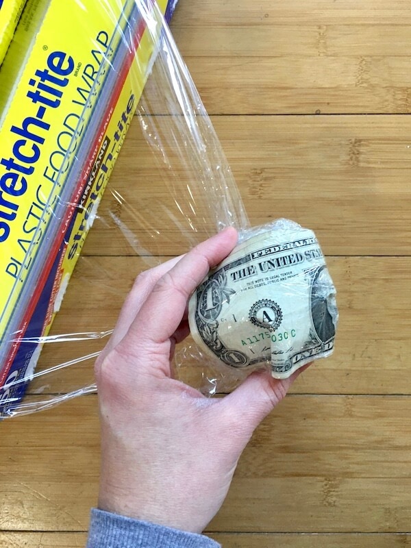 a one dollar bill wrapped up in plastic wrap in the shape of a ball