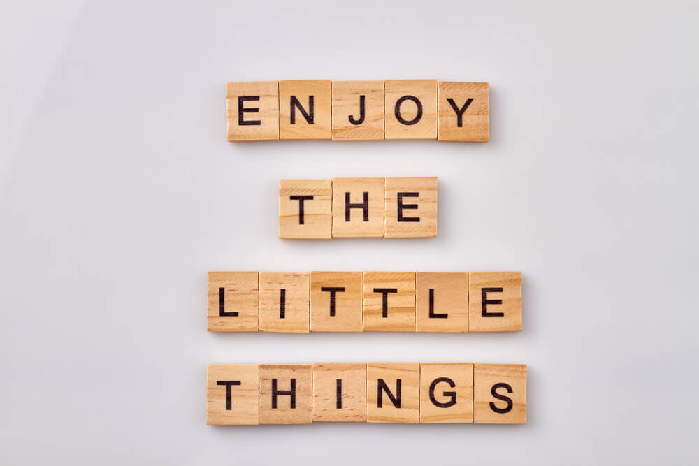 Scrabble tiles that spell out "enjoy the little things"