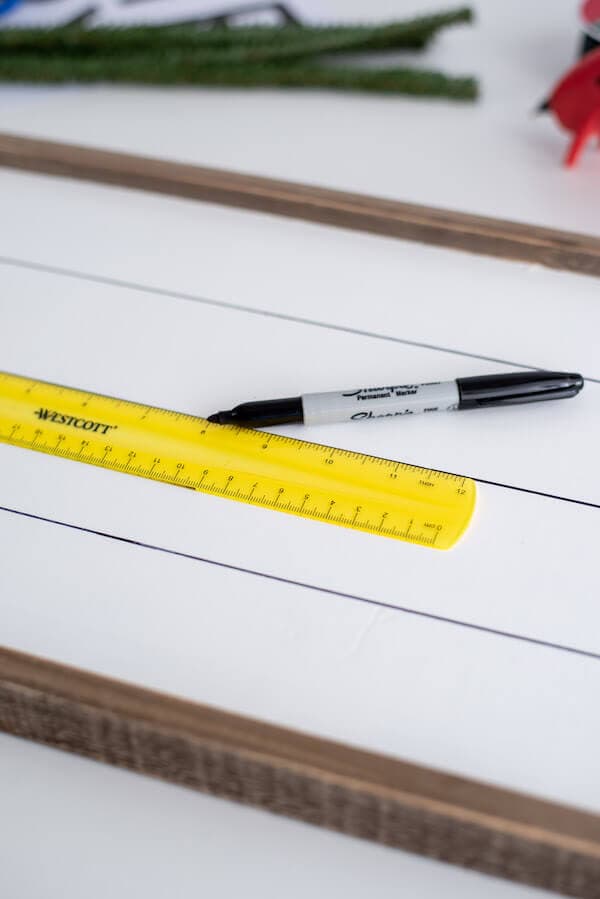 drawing straight lines on a white wooden sign