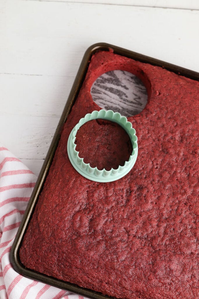 using a circle cookie cutter to cut red velvet cake
