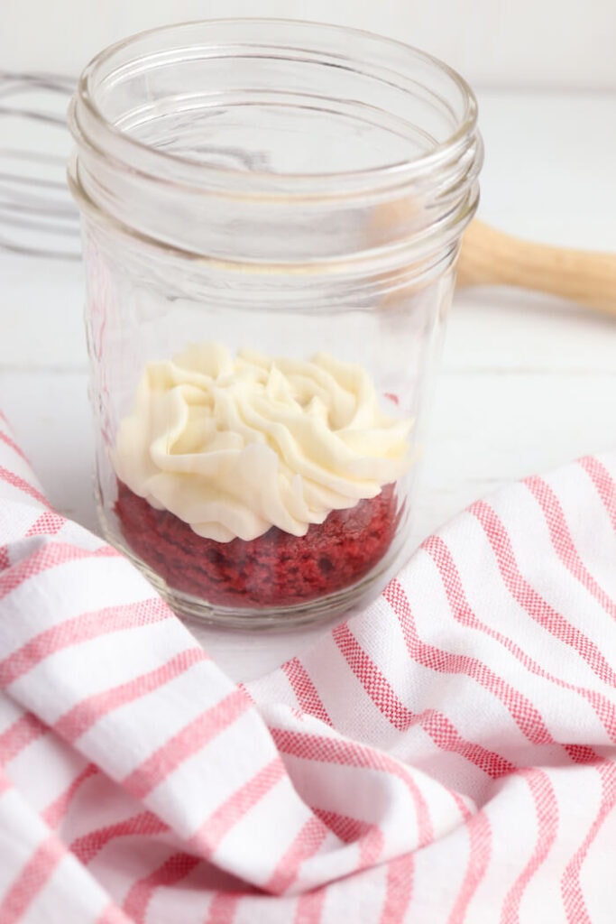 layering cake slices and icing in a mason jar