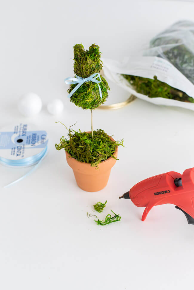 gluing moss into a mini terra cotta pot