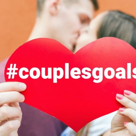 couple kissing holding a heart that says couples goals