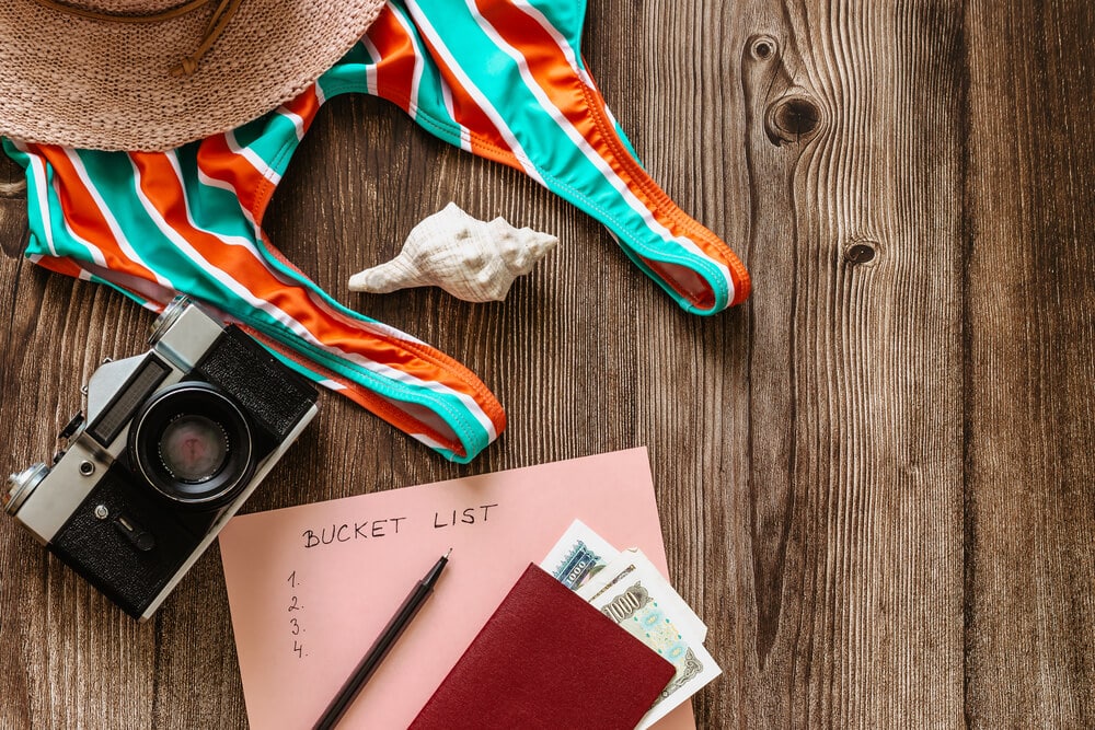 bathing suit, camera, and piece of paper that says bucket list