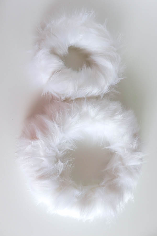two wreath forms wrapped in white fur ribbon
