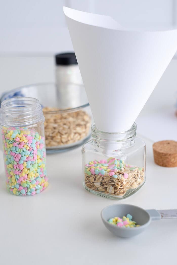 funnel in a glass jar with rolled oats and Easter sprinkles