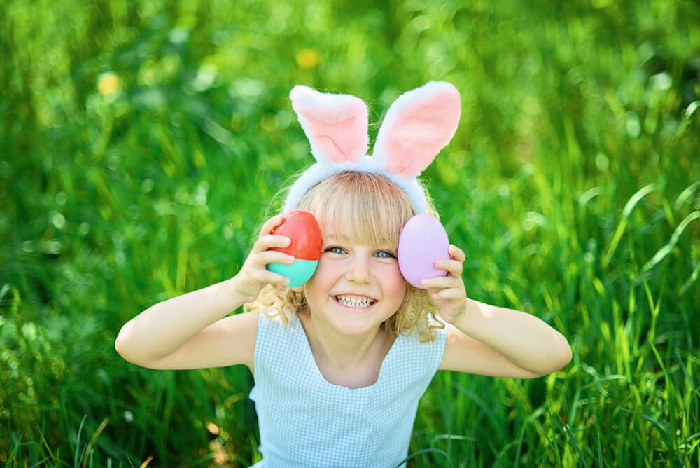 girl holding up two plastic Easter eggs