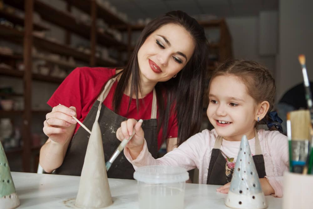 mom and daughter painting pottery together