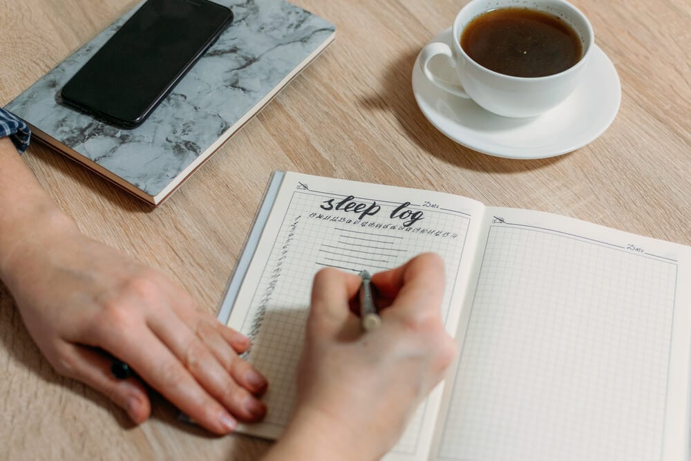 woman writing in a sleep log bullet journal