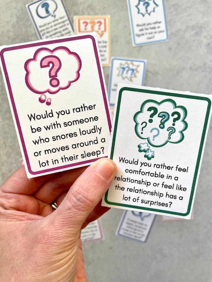 woman's hand holding two would you rather question cards