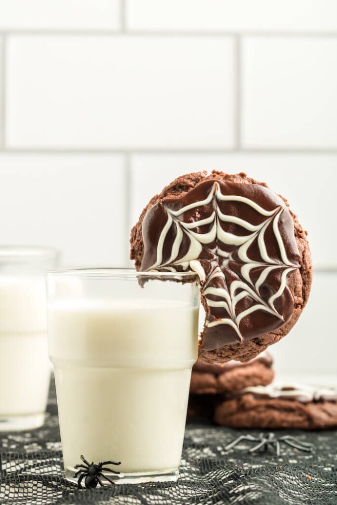 spider web cookie on the side of a glass of milk