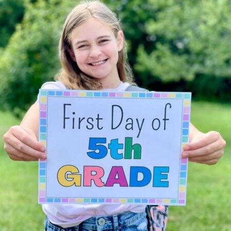 girl holding a printable first day of school sign