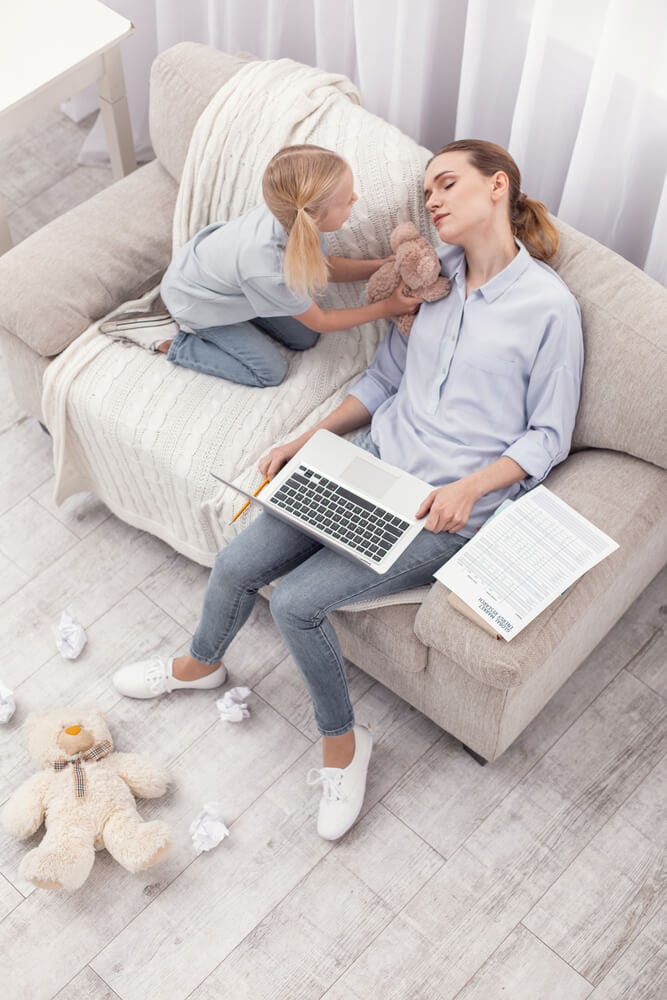 tired Mom sitting on a couch with her child