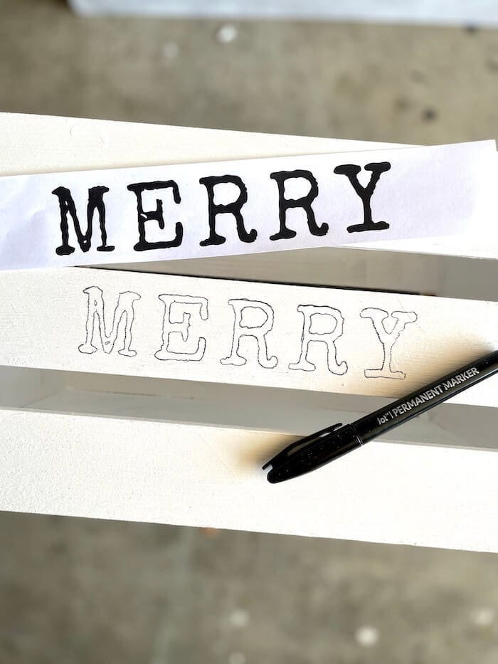 the word merry stenciled on a white wooden crate