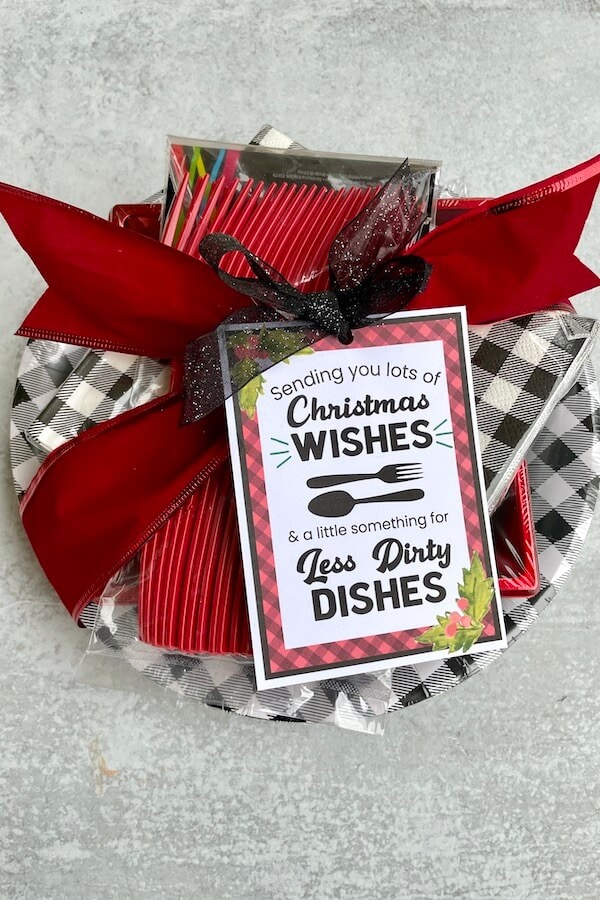 paper plates and napkins wrapped in a bow with a "less dishes" Christmas gift tag