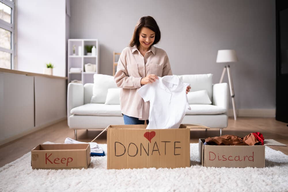 woman sorting clothes into boxes to declutter