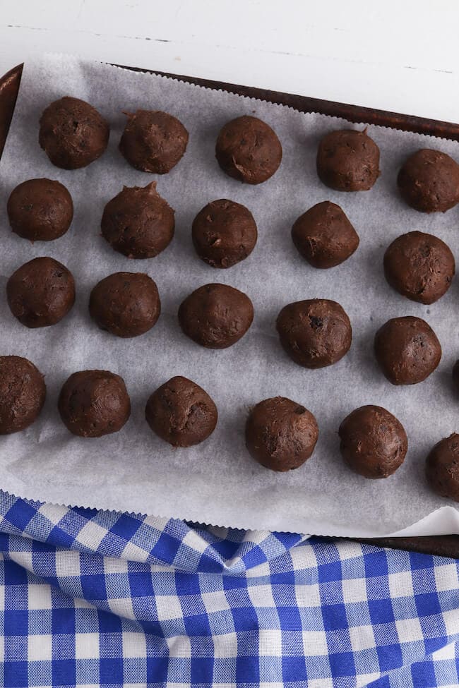 rolled balls of brownie mix on a sheet pan