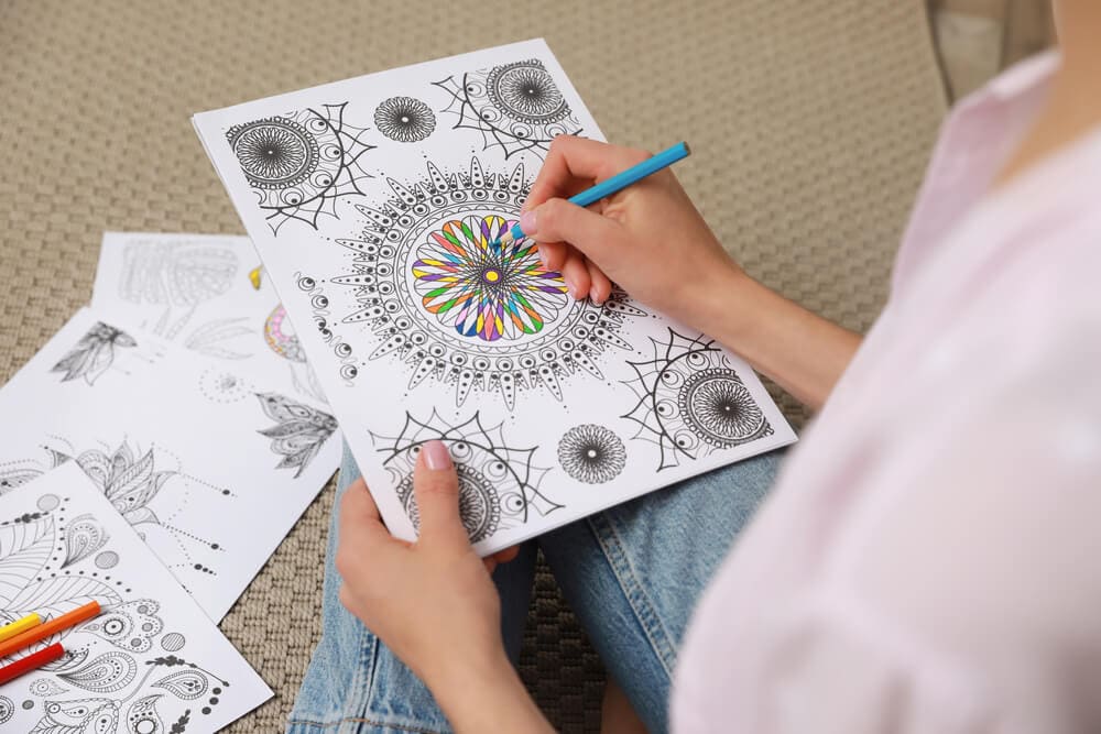 woman coloring an adult coloring page with colored pencil