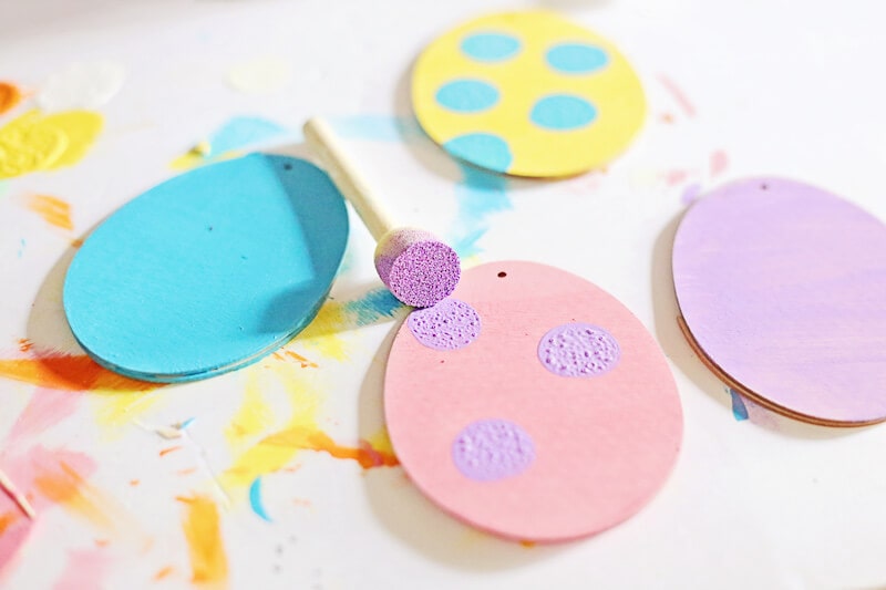 painting polka dots on wooden Easter egg ornaments