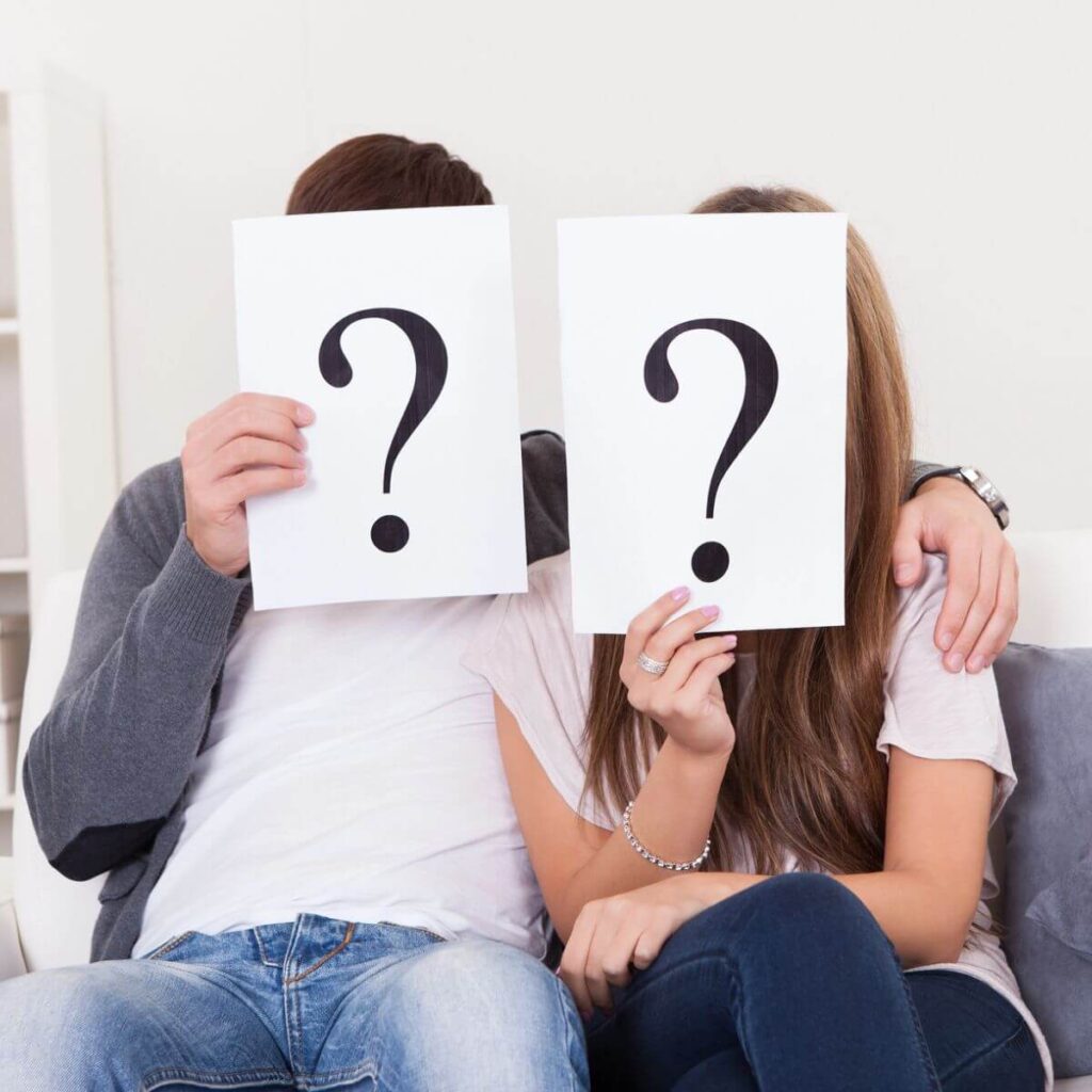 couple sitting on a couch holding up question cards