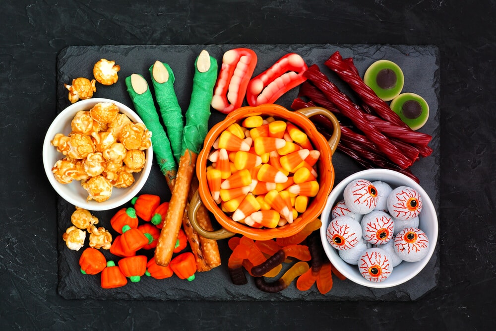 Halloween snack board with candy corn, caramel popcorn, and other snacks