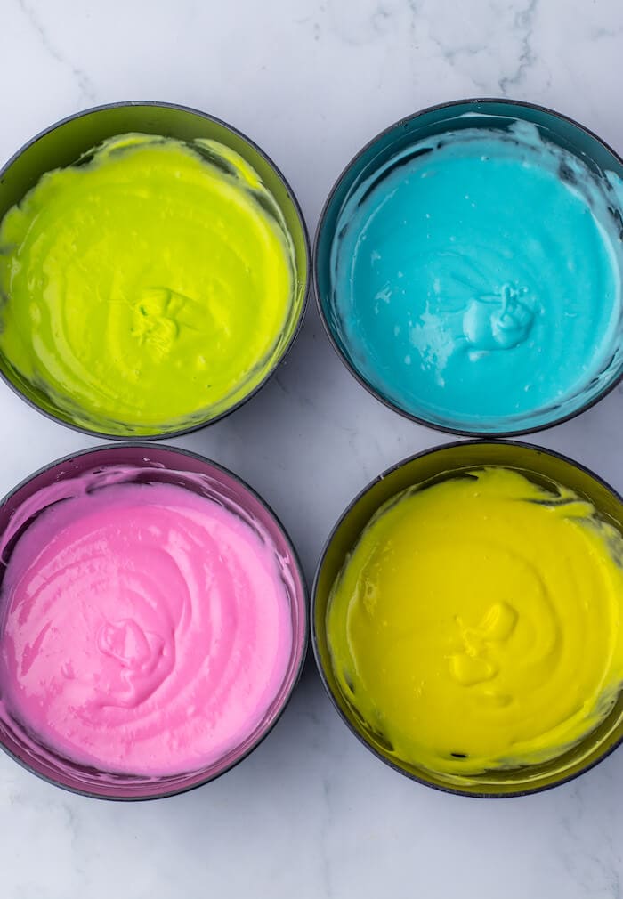 four colors of cake batter in bowls