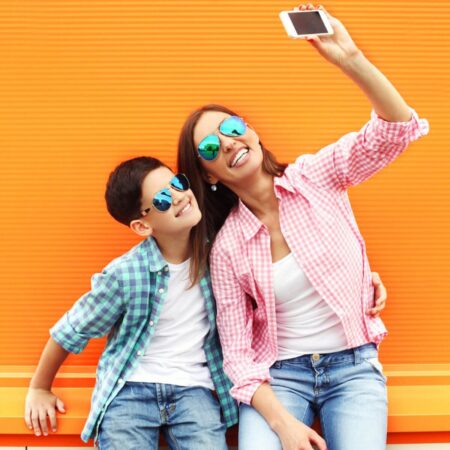 mother and son wearing sunglasses and taking a selfie on a date