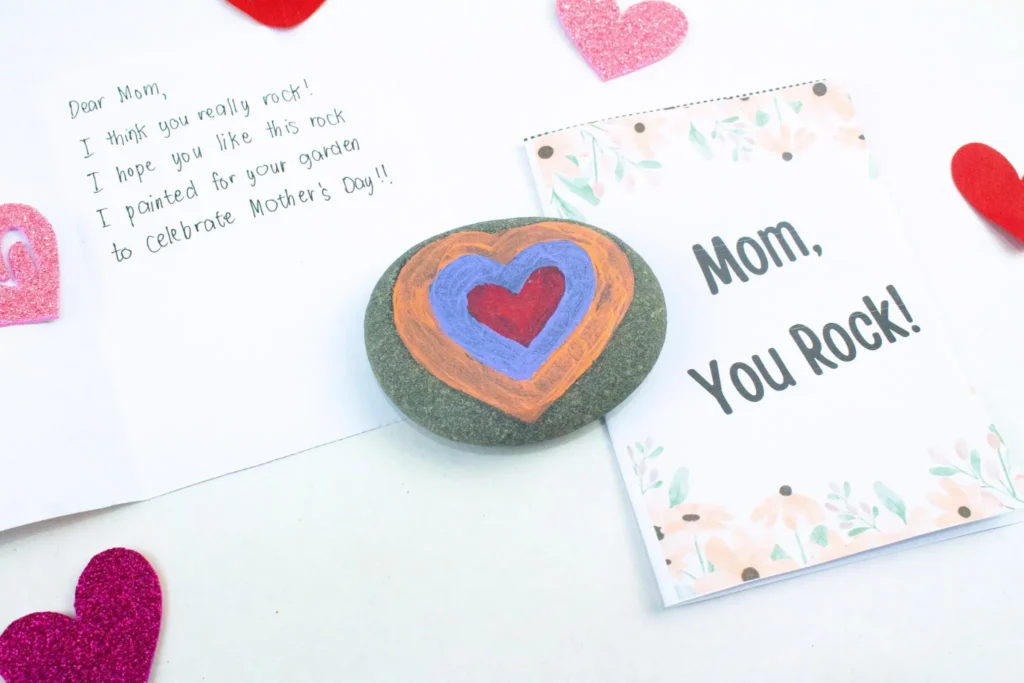 painted rock with a heart and a "mom you rock" card