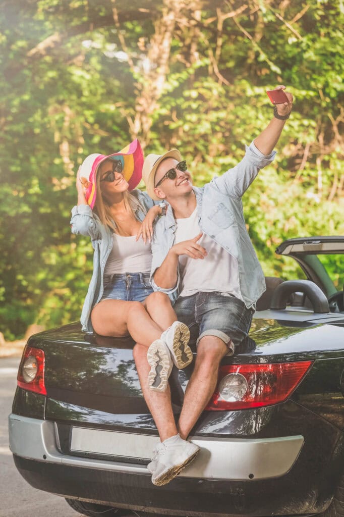 couple taking selfies sitting on the back of a car