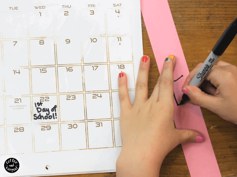 child writing numbers on a strip of paper to make a countdown for back to school