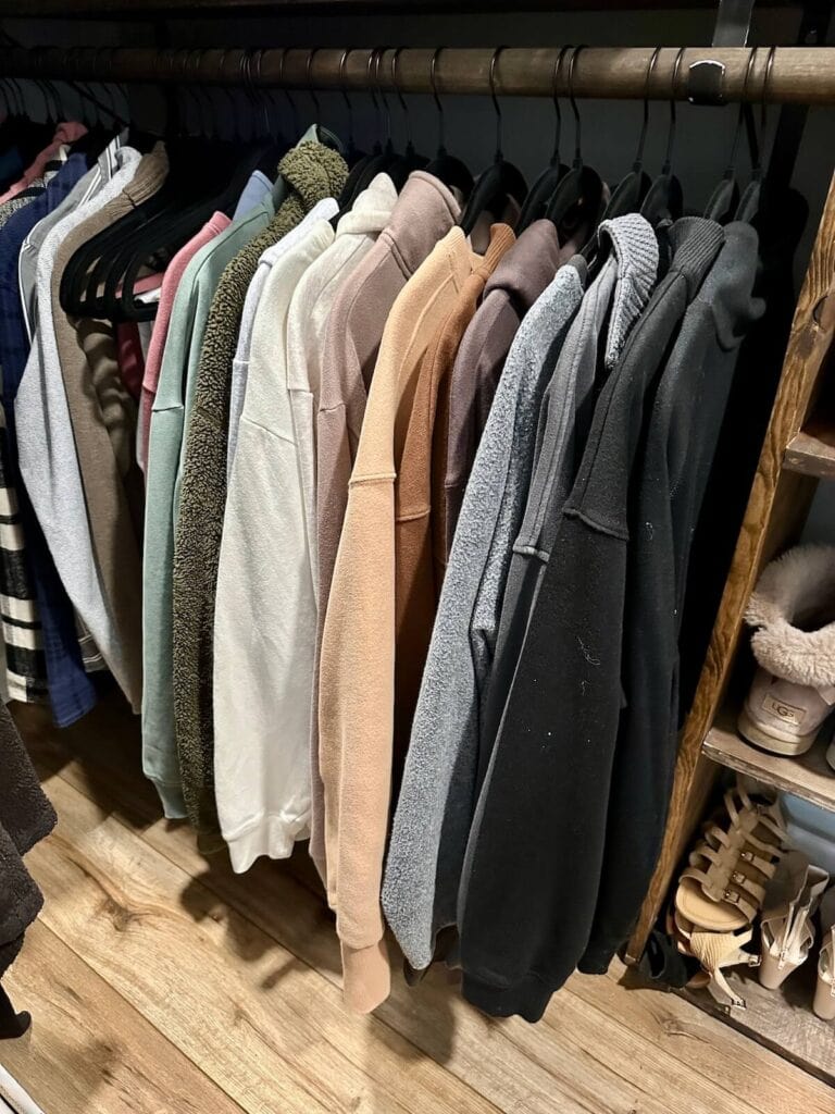 sweaters hanging in closet organized by color