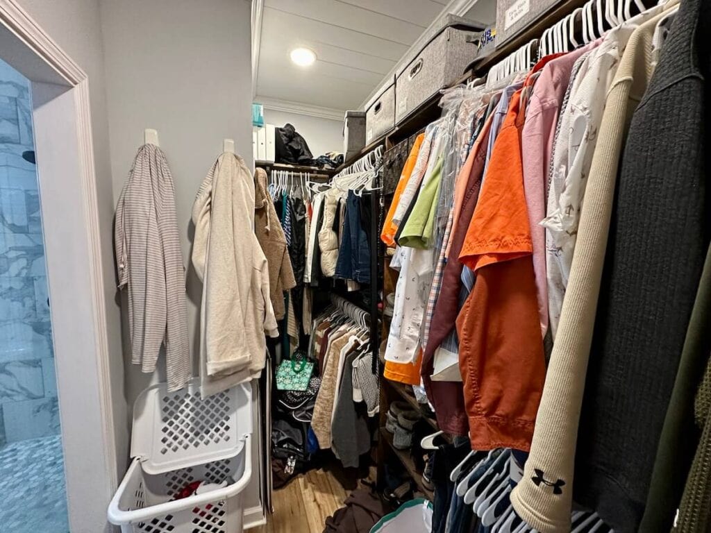 messy small closet with a lot of hanging clothes