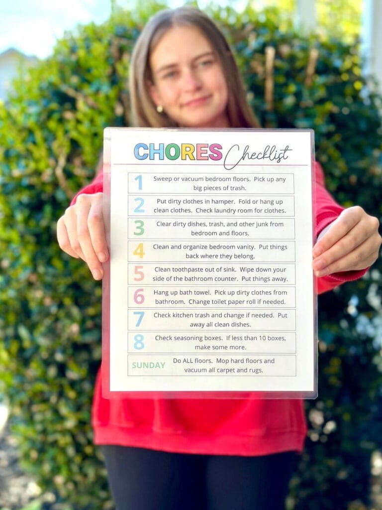 teen girl holding up a laminated chore checklist