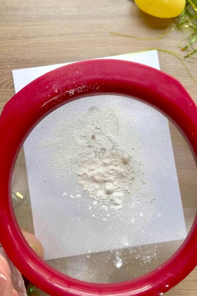sifting flour over a paw print stencil