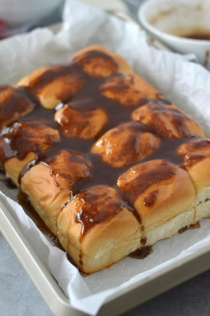 cinnamon roll filling spread on top of Hawaiian rolls