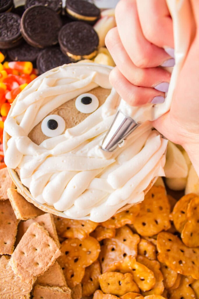 decorating a peanut butter dip to look like a mummy