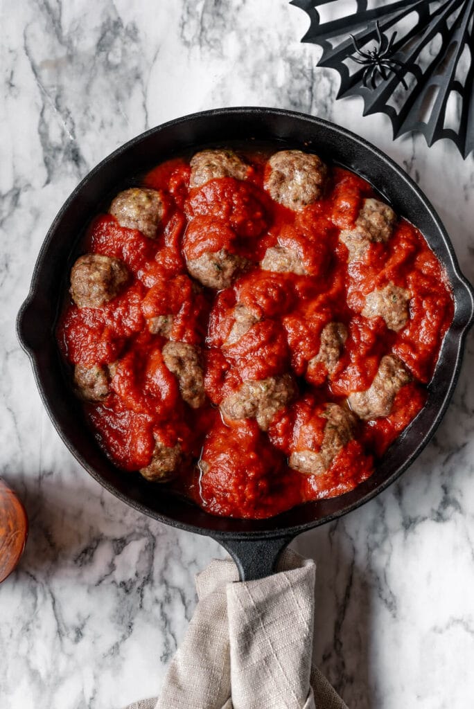 making meatballs and marinara in a skillet