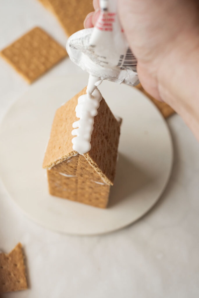 adding icing to a graham cracker roof for a gingerbread house
