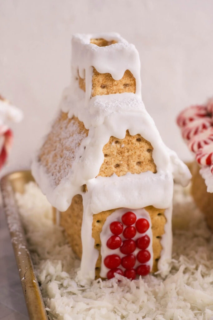 gingerbread graham cracker house with white icing and red hot candies
