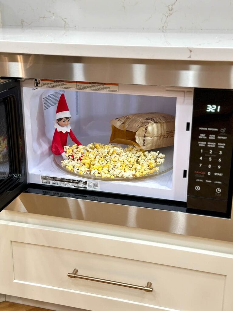 elf on the shelf inside a microwave with popcorn
