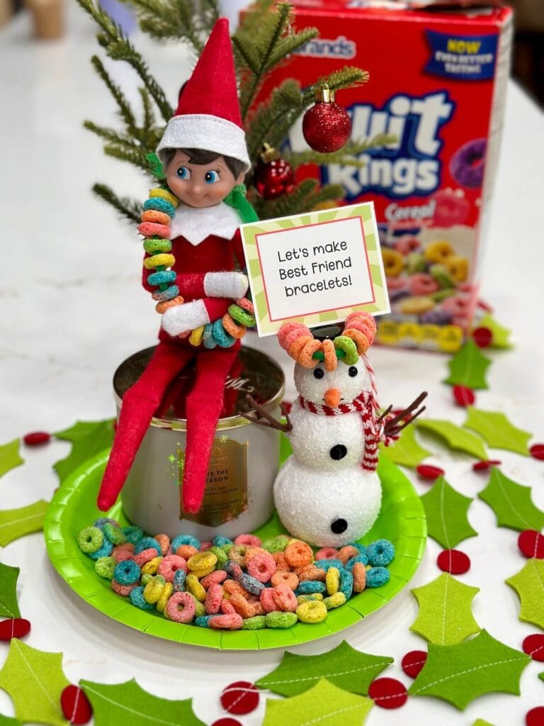 Elf on the Shelf with Froot Loops and a sign that says let's make friendship bracelets