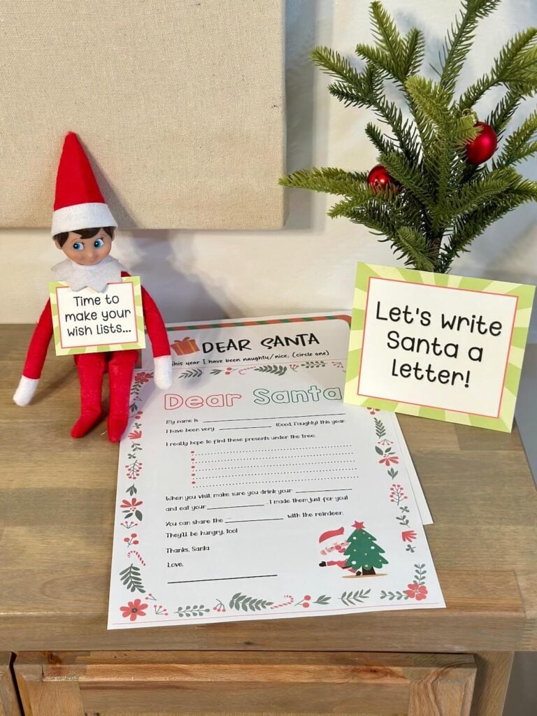 Elf on the Shelf with a sign that says let's write Santa a letter with a free printable Santa letter template