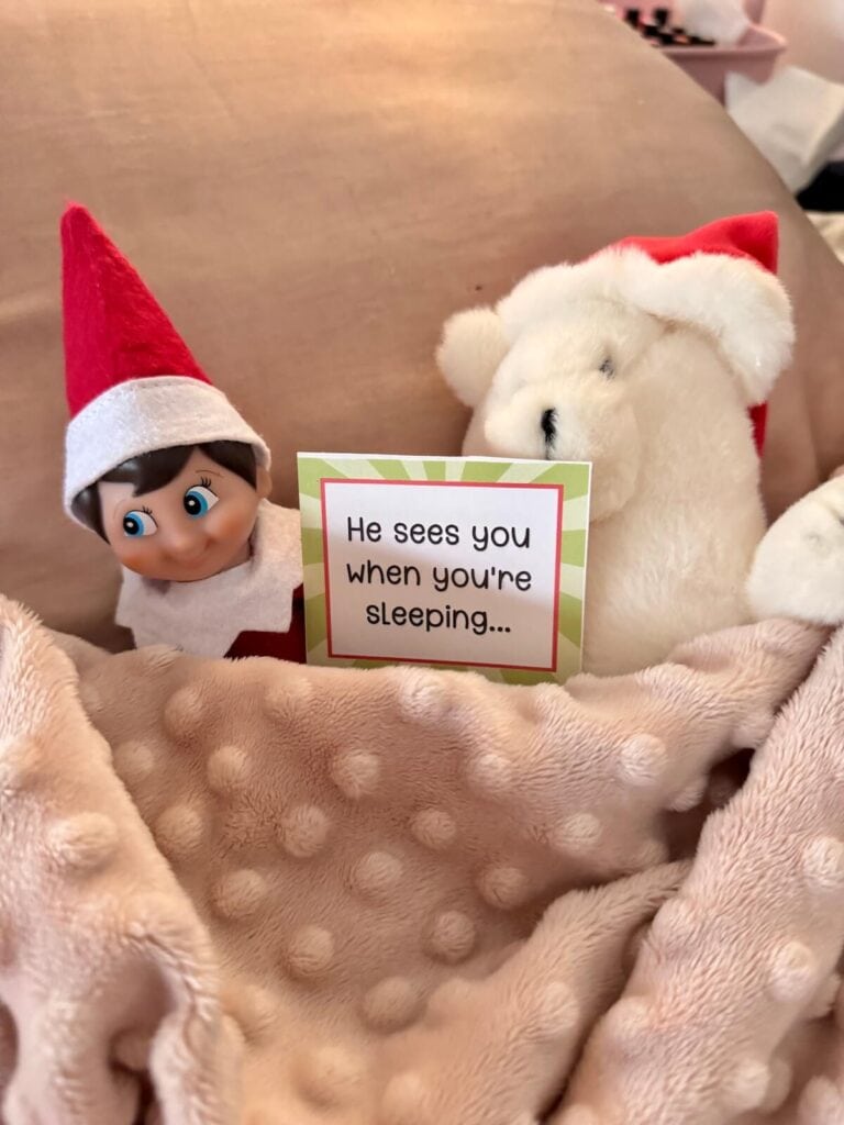 Elf on the shelf sleeping under a blanket